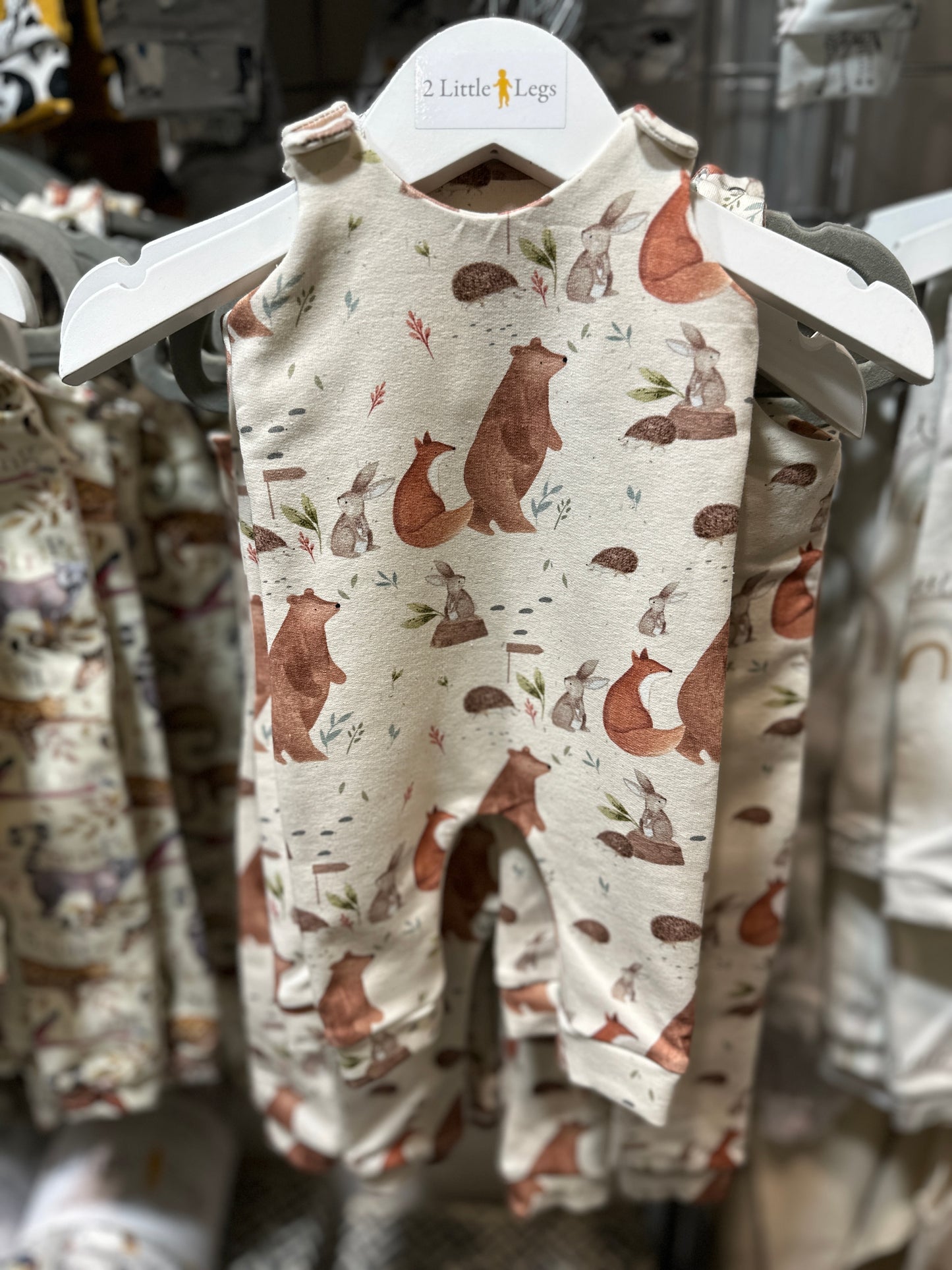 Childs romper featuring a forest animals pattern on a hanger