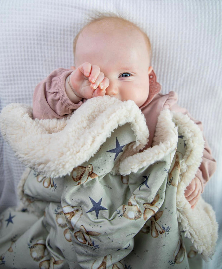 A baby under a fleece blanket
