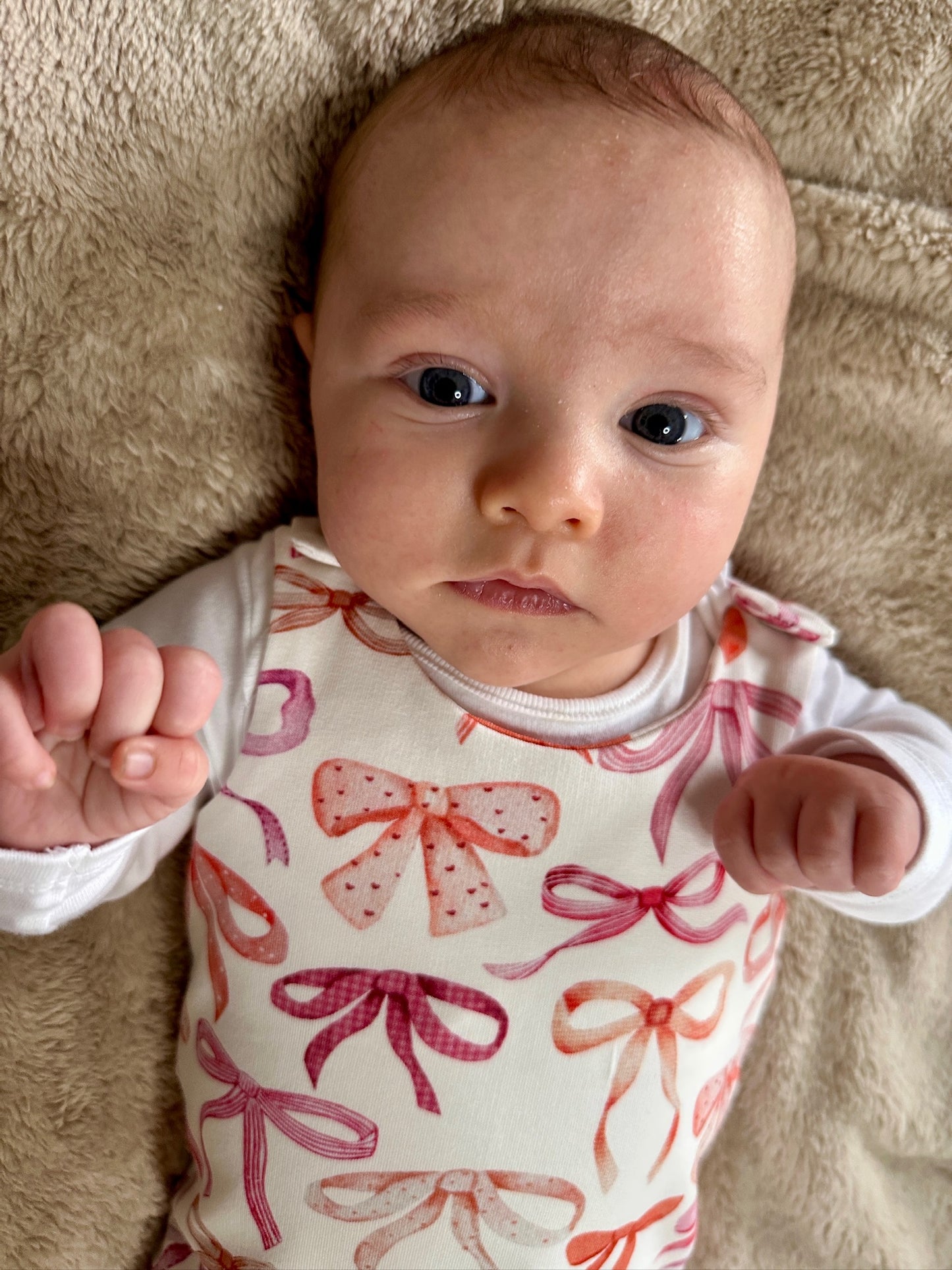 Baby wearing a romper with pink and red bow pattern
