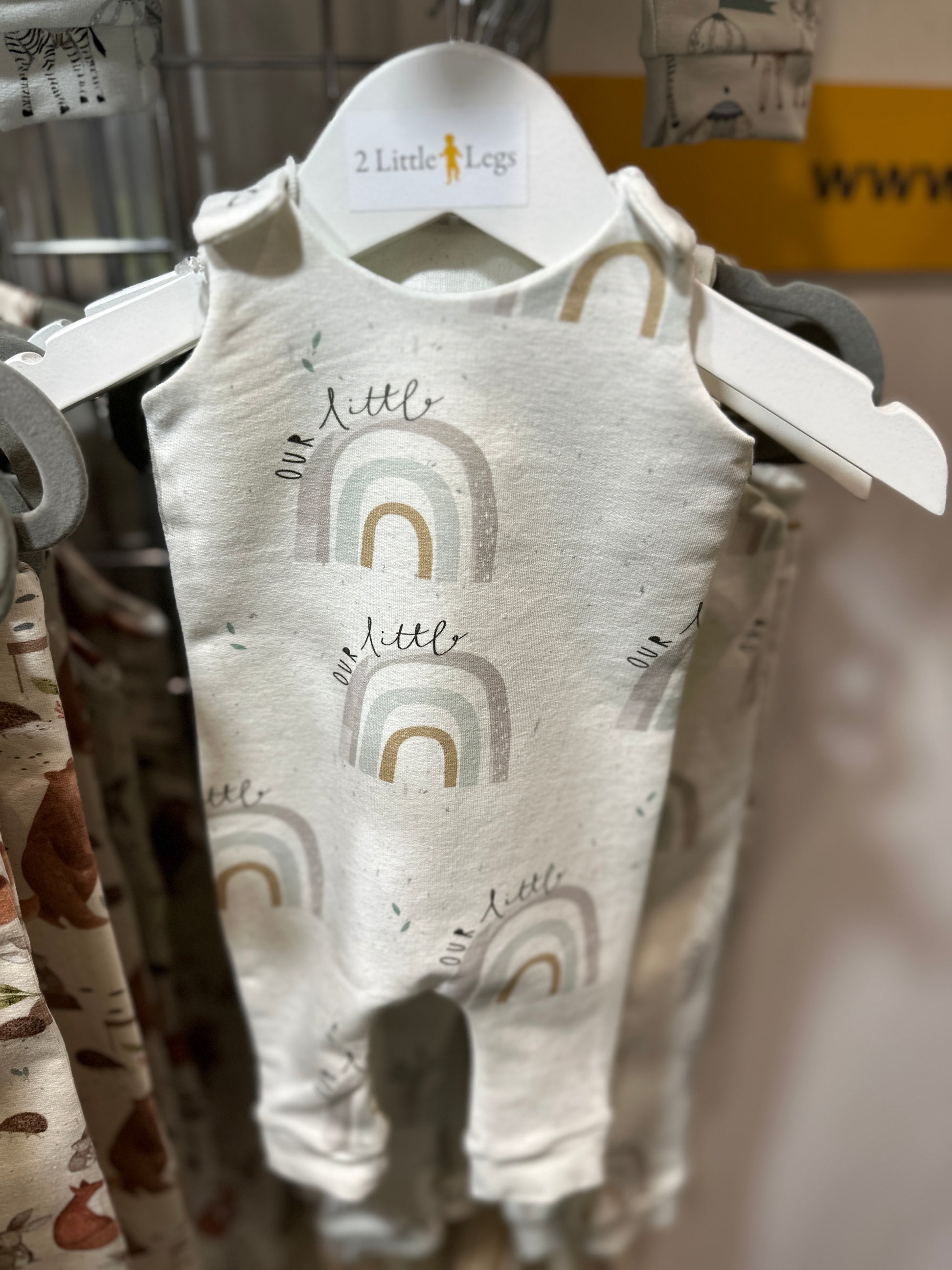 Childs romper with a rainbow pattern on a hanger