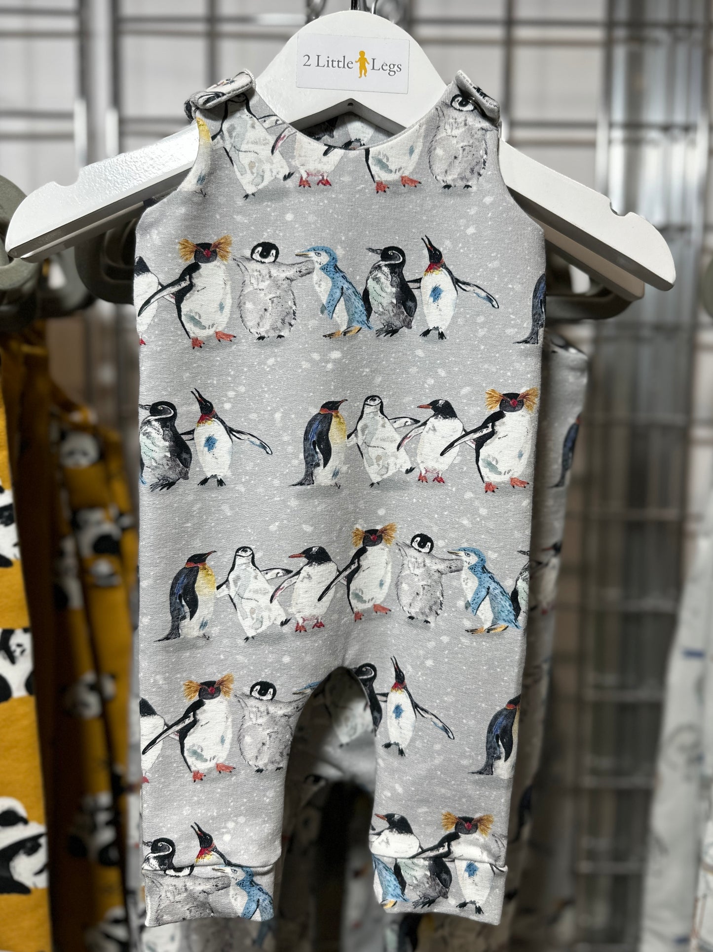 Childs romper featuring a penguin pattern on a hanger
